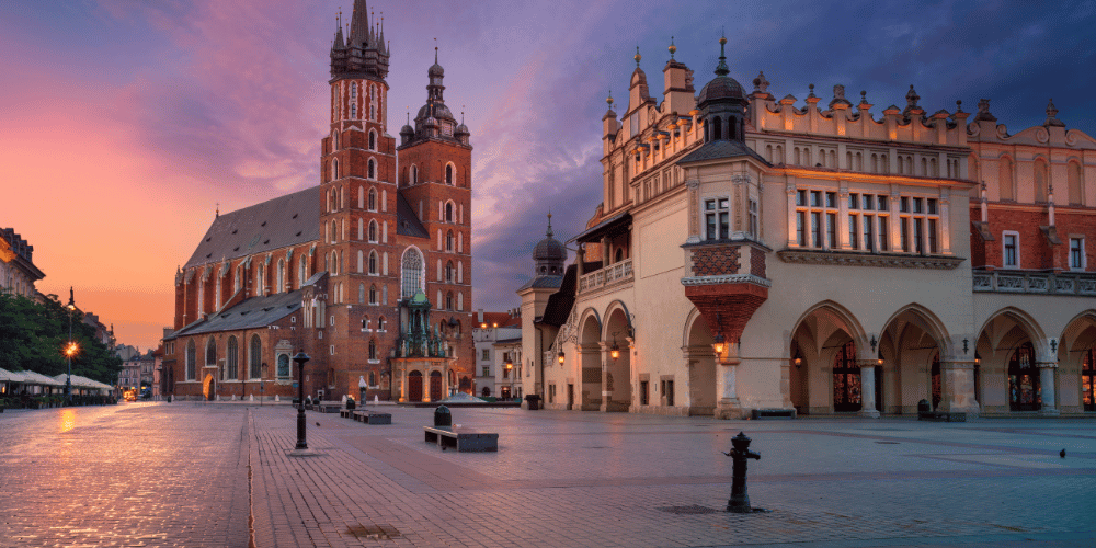 The city square in Krakow, Poland, bathed in warm sunset hues, showcasing its architectural beauty and lively atmosphere