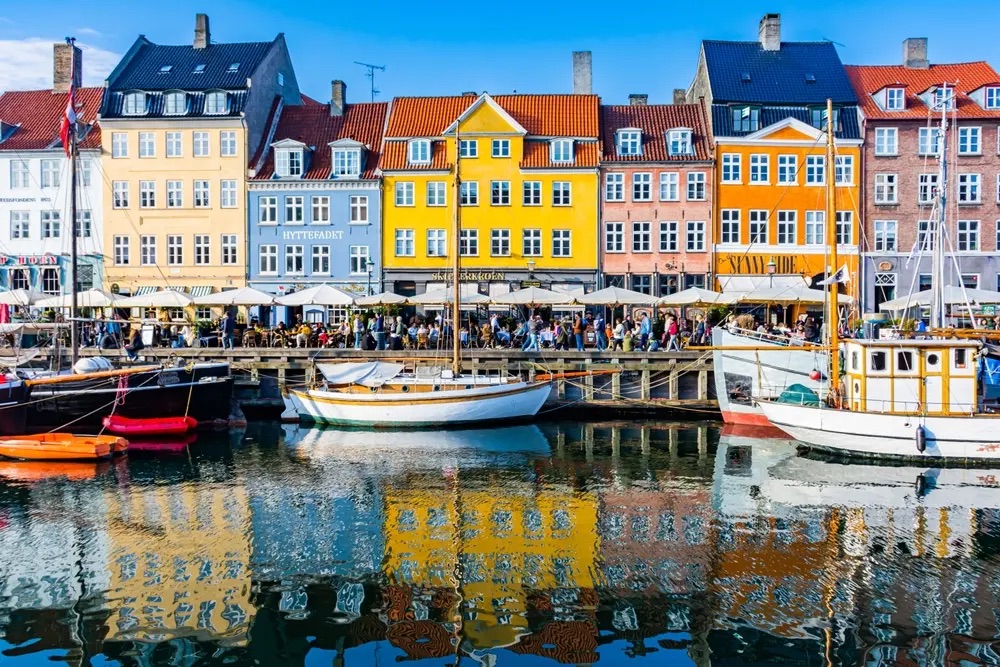 Colorful buildings and boats line the waterfront in Copenhagen, Denmark, showcasing the city's vibrant architecture