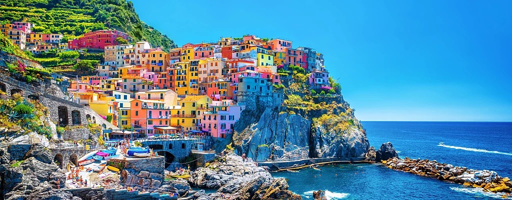 Brightly colored houses line a cliff by the ocean, offering a stunning view of the water and surrounding landscape